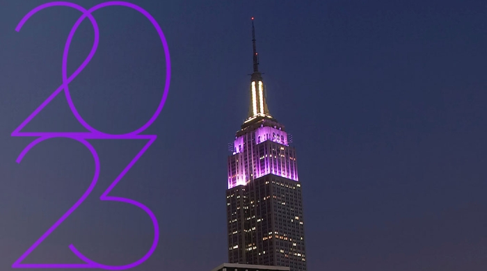 2023 text over a photograph of the Empire State Building light up purple