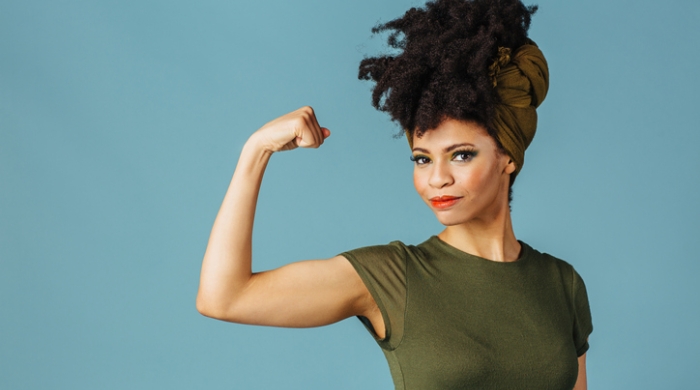 A Black woman flexing her bicep, showing strength.