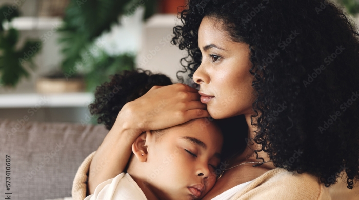 image Captures the side profile of a Mother's face, as she holds her elementary school aged child in her arms