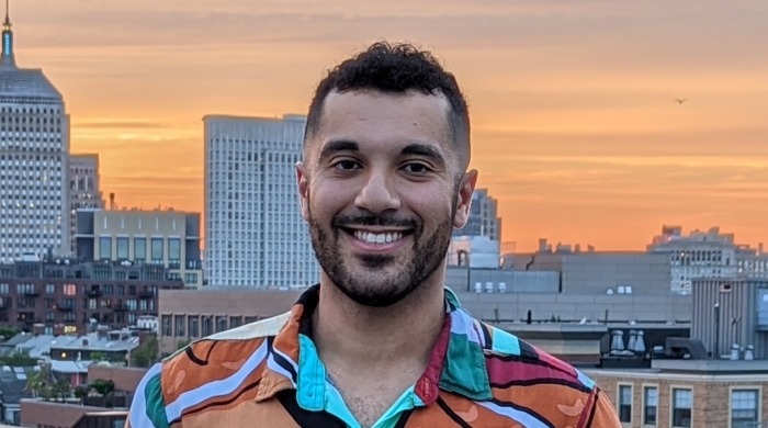 photo of Ramy smiling with a city and sunset in the background