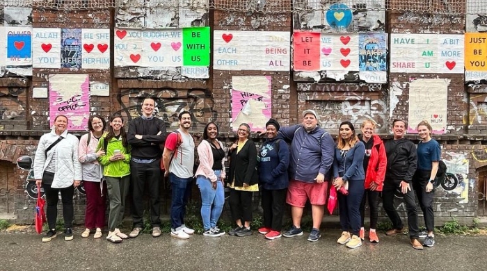 A group of Astor Fellows stand in front of a wall with encouraging and uplifting signs on it