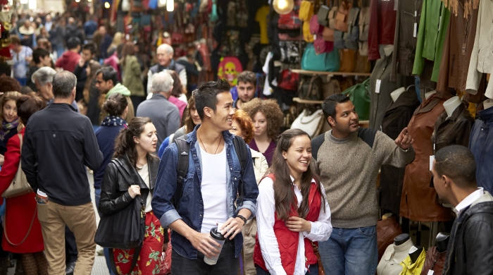 Students walk through a busy and colorful market in Florence, Italy.