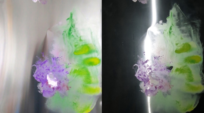 Two images of the same work appear next to each other. The work is a painting on a sheet of steel. Purple and green paint are smeared all over the steel. On the left, the painting is sown in the light. On the right, it's shown in the dark.