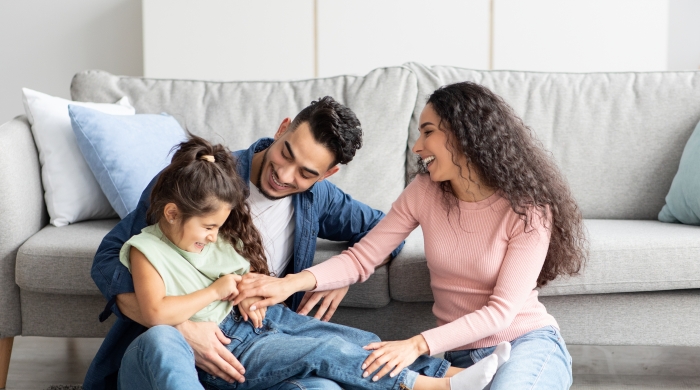 A mother and father attend to their daughter, as they play and hold her.