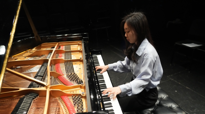 Woman playing grand piano with a view of the inside of the piano