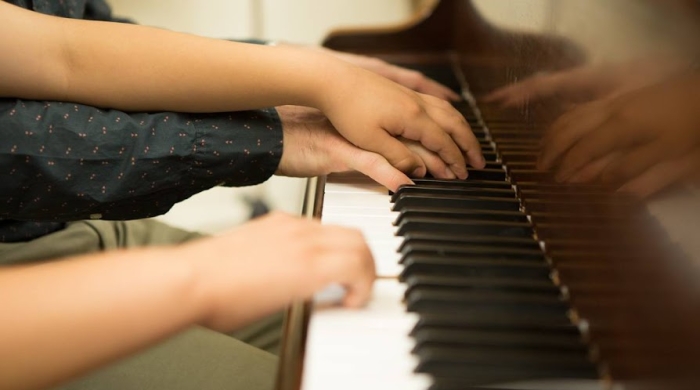Grown up hands and a child's hand playing piano