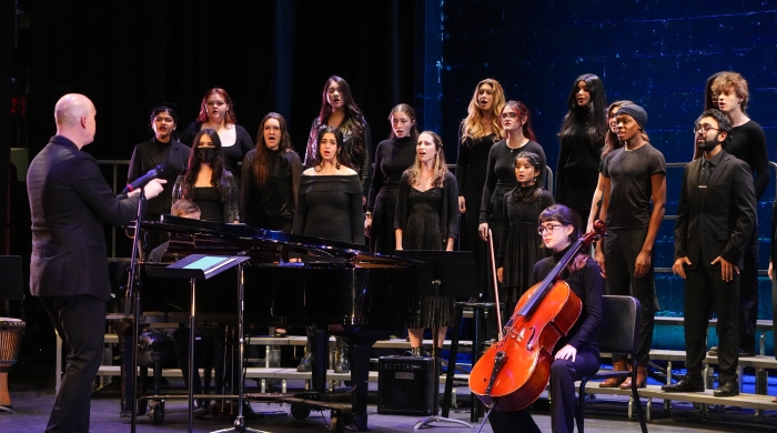 Chorale students performing on stage with a cello player