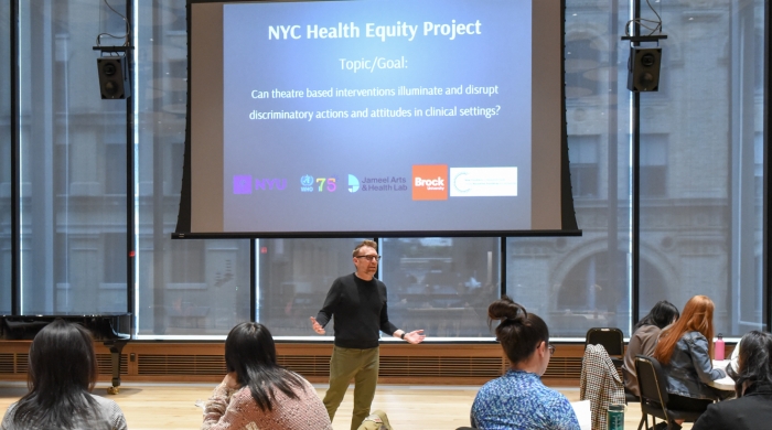 Joe Salvatore speaks to event attendees in front of a projector that reads, NYC Health Equity Project