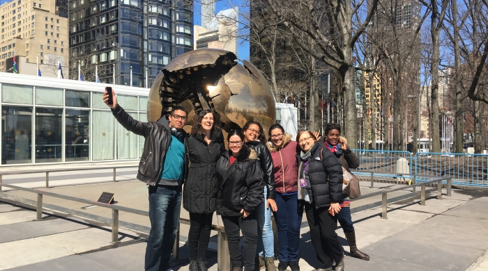 A group of IPA students, faculty, and NYU faculty in front of a sculpture at the United Nations