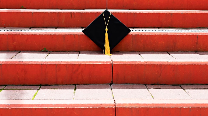 Black Graduation Cap on Red Staircase