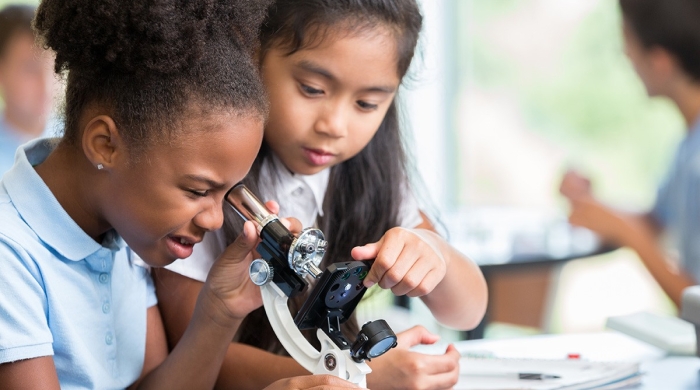 Two young students use a microscope