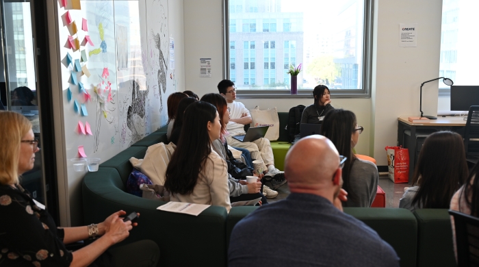 Attendees sit on a couch during a presentation
