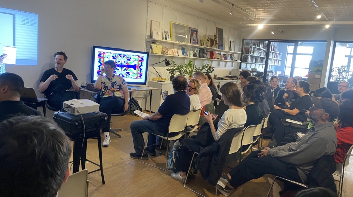 Audience members face Whit Pow and Alexander Galloway as both scholars wait to begin their talks.