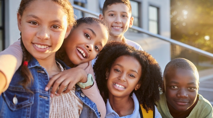 A selfie photo of a group of friends outside of a school. 