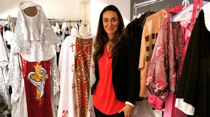 Costumer designer standing in front of racks of costumes