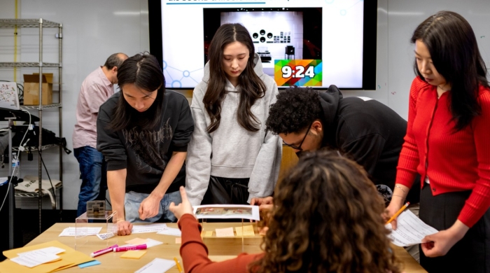 Students work around a table with a slide in the back reading "The Sound and Music Museum" opens in 30 minutes