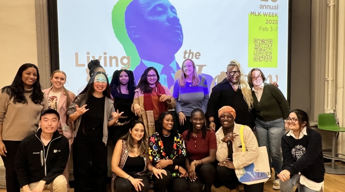 A group of people poses for the photo in front of a projector screen with a photo of Martin Luther King, Jr.
