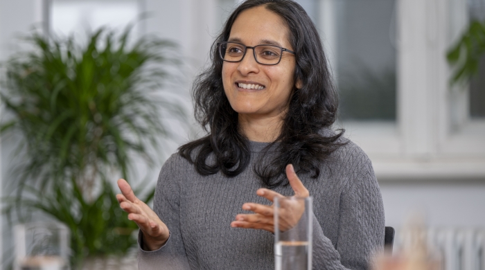 A candid photo of Dr. Sudha Arunachalam smiling and gesturing with her hands as she speaks.