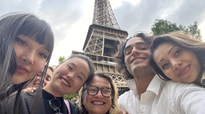Students post for a selfie in front of the Eiffel Tower in Paris. 