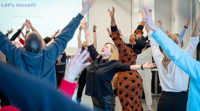Deb Damast and a group of dancers reach their arms into the air