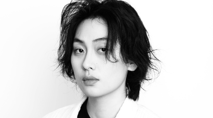 Black and white image of Jing Cheng center frame, looking into camera. Jing has black hair and white shirt