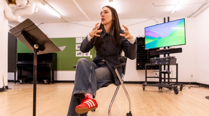 Student speaking in front of colorful screen and music stand
