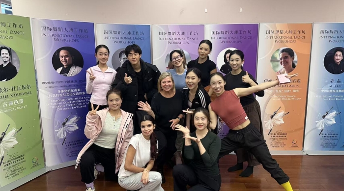 Deborah Damast and a group of students pose for the photo in front of event posters