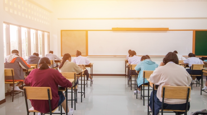 Several rows of students sit at desks and focus on their work.