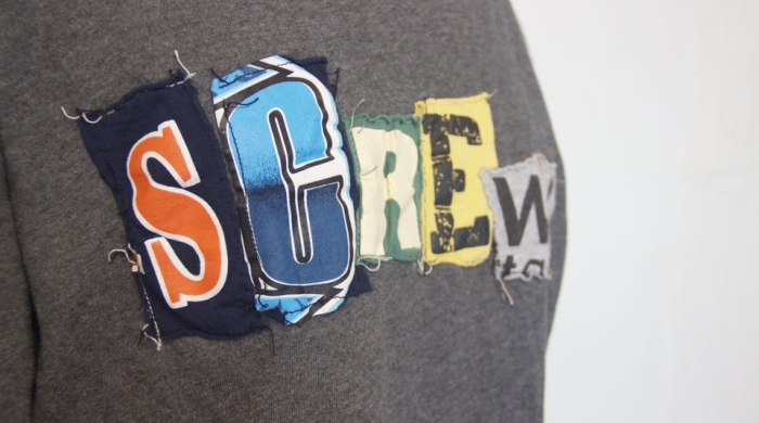 Close up image of a t-shirt with letters that spell out the word "screw"