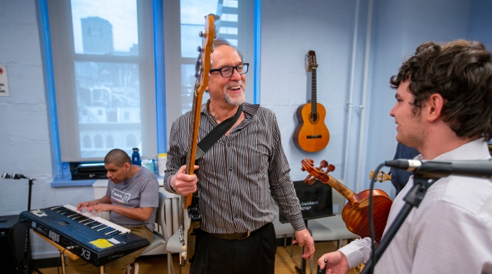 Prof Alan Turry holding guitar laughing with student