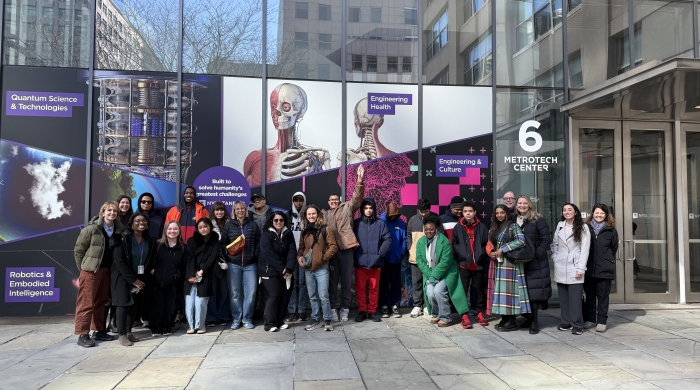 A large group poses for the photo outside the NYU Metrotech center