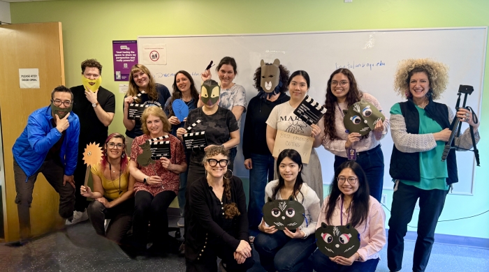 15 people smily for the photo, many wearing or holding paper animal masks
