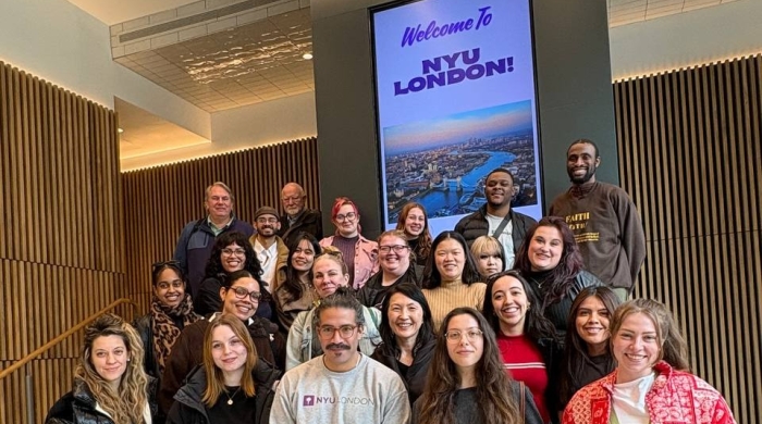 A group of VAA students stands in front of a sign reading "Welcome to NYU London!"