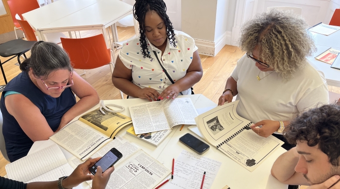 A group of students sit around a table, looking at magazines and newsletters