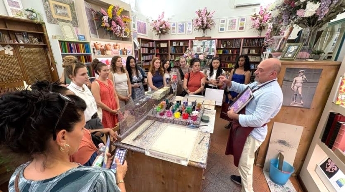 Students watch a painting demonstration in a store in Florence