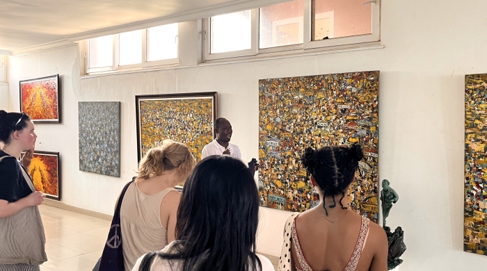 A group of students stands in an art gallery, listening to a docent