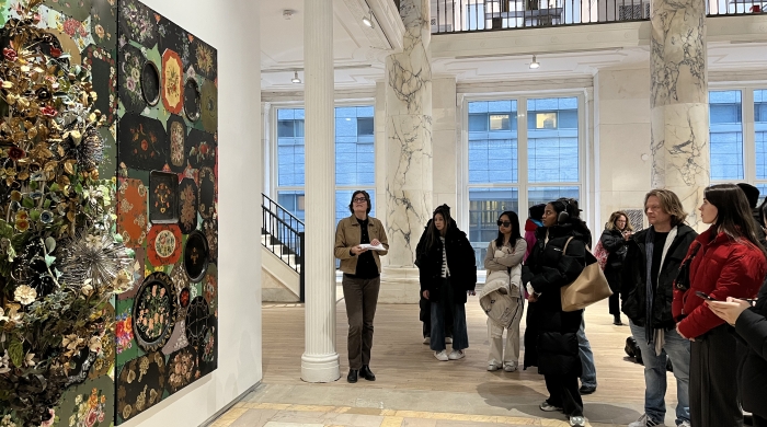 Curator Anna-Michelle Roux stands in front of an artwork with a group of VAA students.