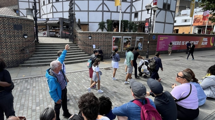 A tour guide points out the Globe Theatre