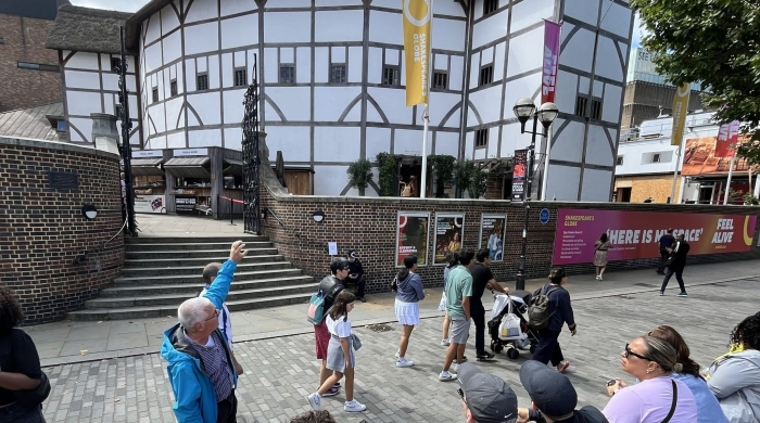 A tour guide points out the Globe Theatre