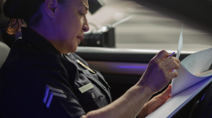 Police offer in car looking at paper on clipboard