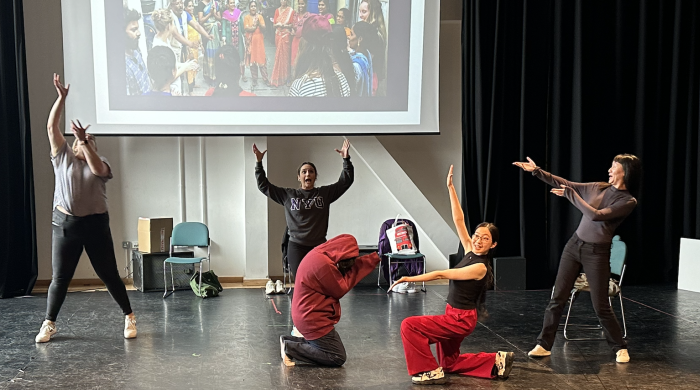 Students doing dance moves in front of pull down screen