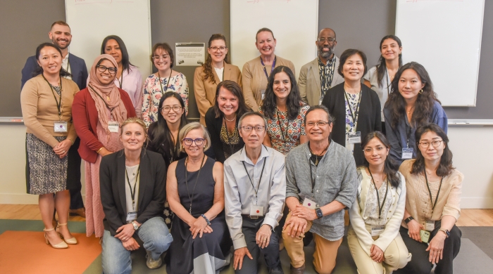 A group of 20 attendees huddle together at the NYU Learning Exchange.