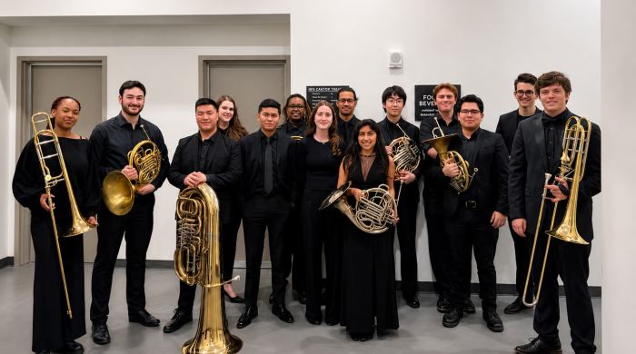 Brass Studies students posing for group photo before concert. Dressed in black and holding instruments.