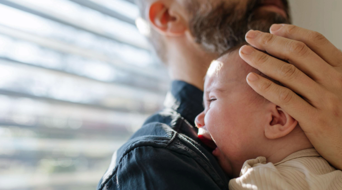 Baby cries on shoulder of father
