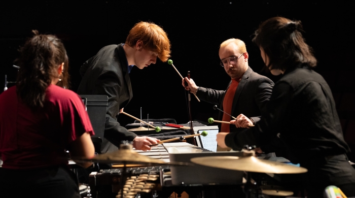 Four students playing percussion instruments on stage