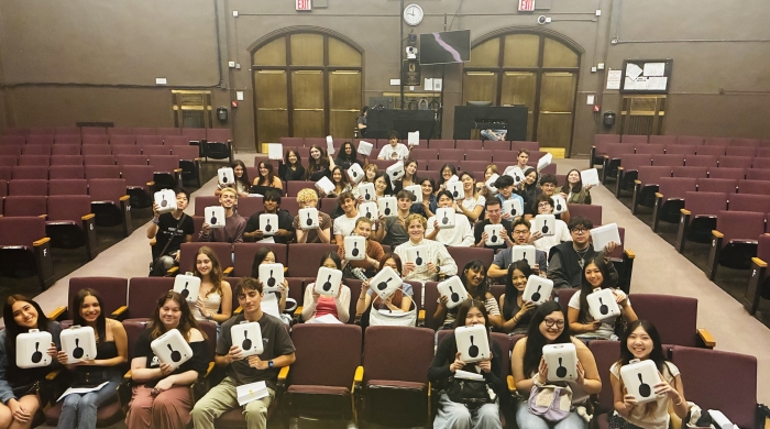 Students holding up Sony 1000XM6 headphones in the Frederick Loewe Theatre.