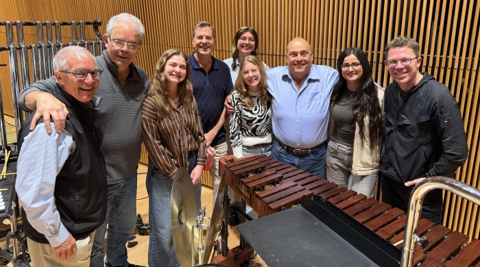 Percussion students posing with faculty in orchestra venue setting