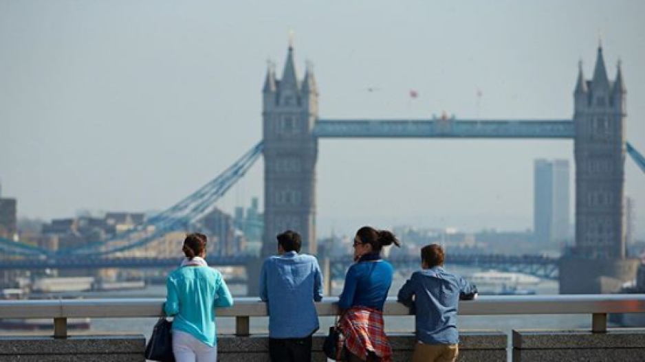 Four people standing facing the London Bridge.
