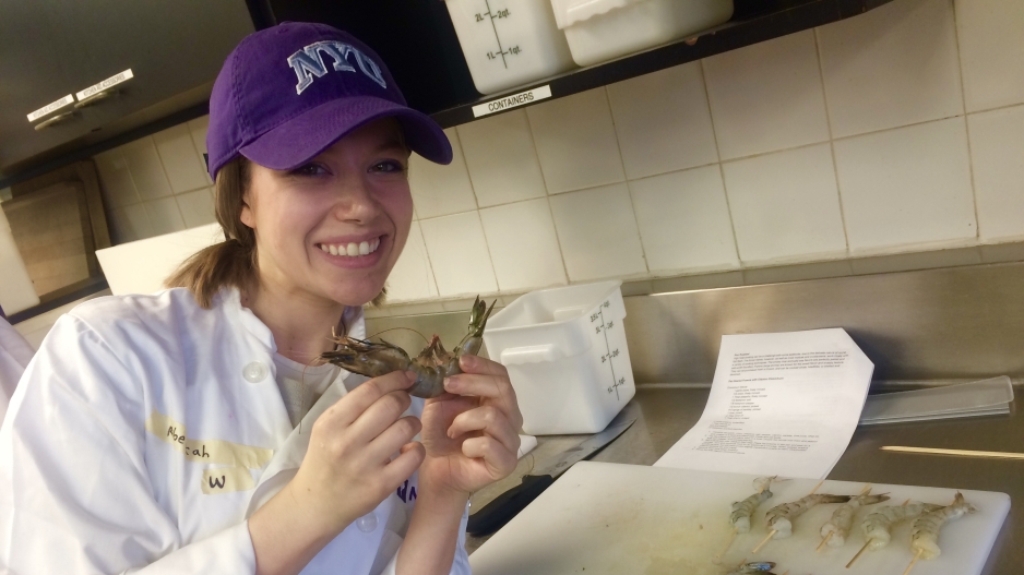 A student posing with a raw shrimp.