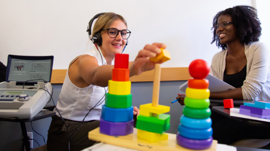 Students using audiology equipment and rainbow colored blocks.